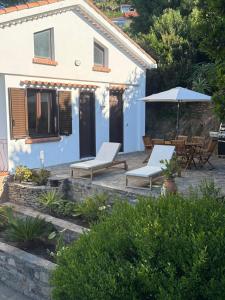 a blue house with two chairs and an umbrella at Villa Rosette Ile du levant in Hyères