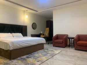 a bedroom with a bed and two chairs and a table at Adwels Hotel&Suites in Akure