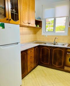a kitchen with wooden cabinets and a white refrigerator at Seren Apartment in Vlorë
