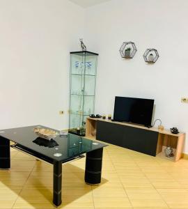 a living room with a glass table and a tv at Seren Apartment in Vlorë