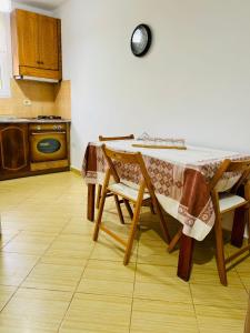 a kitchen with a table with chairs and a clock on the wall at Seren Apartment in Vlorë