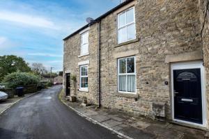 a brick house with a black door on a street at 2 Bedroom Cottage By Cozy Quarters Property Management Holiday Lets Wolsingham Near River Waskerley in Wolsingham