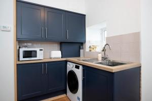 a kitchen with blue cabinets and a washing machine at 2 Bedroom Cottage By Cozy Quarters Property Management Holiday Lets Wolsingham Near River Waskerley in Wolsingham