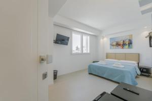 a white bedroom with a bed and a tv at Almarè Affittacamere in Favignana