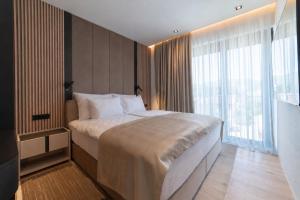 a bedroom with a large bed and a large window at Home apartments in Mostar