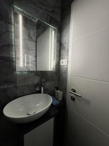 a bathroom with a white sink and a mirror at Apartment Zart 1 in Dekani +3 photos