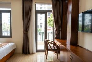 a bedroom with a bed and a desk with a television at An Phú Nguyễn Hoàng Hotel in Hanoi