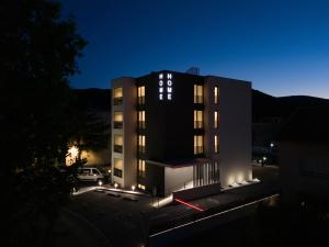 a black building with lights in a parking lot at night at Home apartments in Mostar