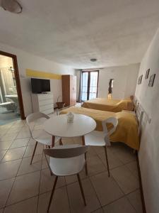 a hotel room with two beds and a table and chairs at Foresteria Kiki in Gravedona +13 photos
