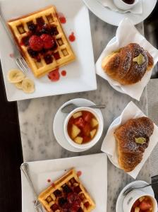 a table topped with white plates with waffles and fruit at Hotel Garden Albania in Golem