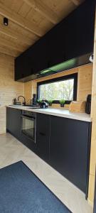 a kitchen with black cabinets and a window at Mazurska Puszcza domek pod brzozą in Dźwierzuty