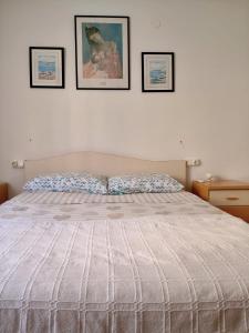 a bed in a bedroom with three pictures on the wall at Paseo el Saladar in Denia