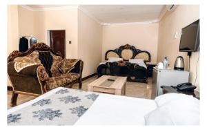 a bedroom with a bed and chairs and a tv at Leon's Lodge in Choma
