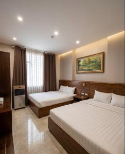 a hotel room with two beds and a window at An Phú Nguyễn Hoàng Hotel in Hanoi