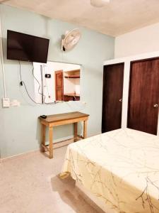 a bedroom with a bed and a table and a tv at Casa Mayan in La Vigueta