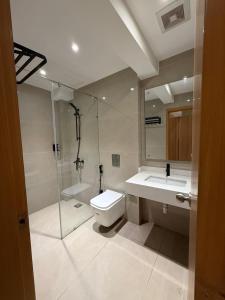 a bathroom with a shower and a toilet and a sink at Hamsun DHA in Karachi