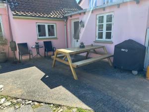 ein hölzerner Picknicktisch vor einem rosa Haus in der Unterkunft Plads til 5 in Samsø + 5 Fotos