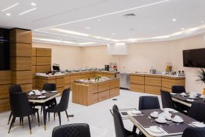 a restaurant with tables and chairs and a kitchen at BON Hotel Kabuwol in Ibadan