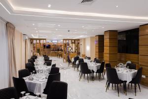 a dining room with white tables and black chairs at BON Hotel Kabuwol in Ibadan
