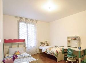 a bedroom with two beds and a desk and a window at Villa Near Versailles in Feucherolles