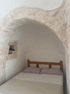 a bed in a white room with a stone wall at Trullo Nunuccio in Ceglie Messapica
