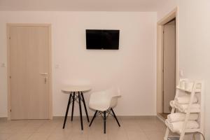 a white room with a table and a chair and a television at Sea Oasis Residence in Limenas