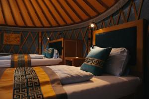 a bedroom with two beds with blue and yellow pillows at Yurt Mongolia - Camp La Belle Vie in Berdorf