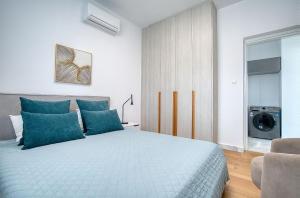a bedroom with a large bed with blue pillows at Modern Sea-View Work Apartment, Sit-Stand Desk, Pool, Gym & Walk to Old Town in Paphos