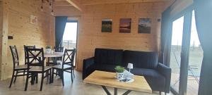 a living room with a couch and a table and chairs at Mazurska Puszcza domek pod brzozą in Dźwierzuty +20 photos