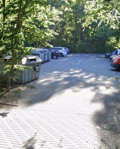 a parking lot with parked cars and a tree at GEM Stay in Oberhausen +8 photos