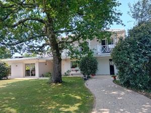 a large white house with a tree in the yard at La Nomade in Andernos-les-Bains