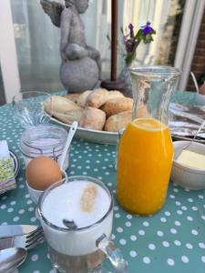 a table topped with a jug of orange juice and a plate of doughnuts at De kleine Bongerd -The little Orchard in Hengelo