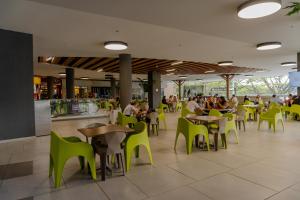 a restaurant with green chairs and people sitting at tables at Cerritos Premium Tower & Mall in Pereira