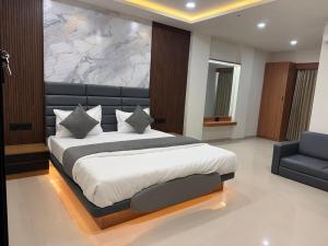 a bedroom with a large bed and a couch at Hotel Peacock Anand in Anand