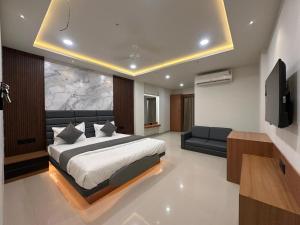 a bedroom with a bed and a tv and a couch at Hotel Peacock Anand in Anand