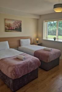 two beds in a hotel room with a window at Large two bedroom apartment Athlone in Athlone