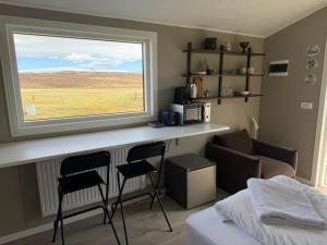 a bedroom with a counter with two chairs and a window at Lífsbót - riverside cottage in Egilsstaðir