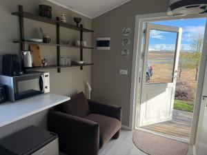 a living room with a couch and a microwave and a door at Lífsbót - riverside cottage in Egilsstaðir