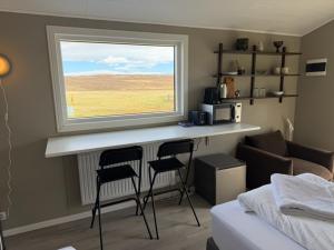 a room with a counter with two chairs and a window at Lífsbót - riverside cottage in Egilsstaðir