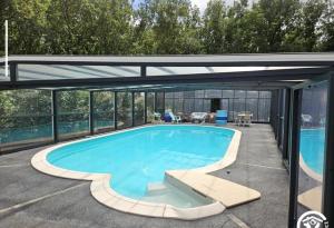 a swimming pool in a house with a glass extension at Maison piscine chauffée in Puybegon