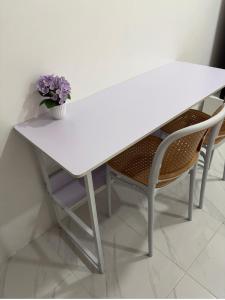 a white table with two chairs and a vase of flowers at Phuket Hostel at Town in Phuket