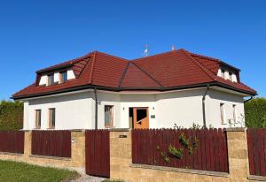 a house with a red roof and a fence at Vila SoHo in Vysoké Mýto