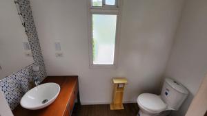a bathroom with a toilet and a sink and a window at Kolibri Containers Boyacá in Guayatá