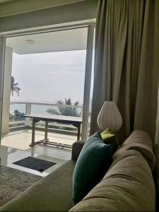 a couch in a living room with a view of the ocean at apartmentleeza in Uswetakeiyawa