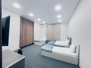 a hotel room with two beds and a television at Center Hotel Darhan in Tashkent