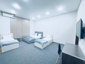 a room with two beds and a flat screen tv at Center Hotel Darhan in Tashkent