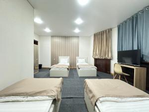 a room with three beds and a flat screen tv at Center Hotel Darhan in Tashkent