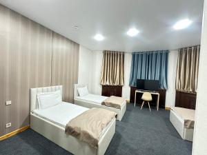 a hotel room with two beds and a desk at Center Hotel Darhan in Tashkent +7 photos
