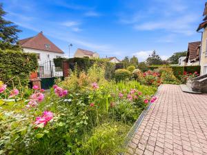a garden with pink flowers and a brick walkway at T3 lumineux, central, parking & confort moderne in Saint-Cyr-lʼÉcole