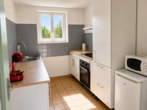 a small kitchen with white appliances and a window at L'échappée Verte in Saint-Jean-la-Bussière
